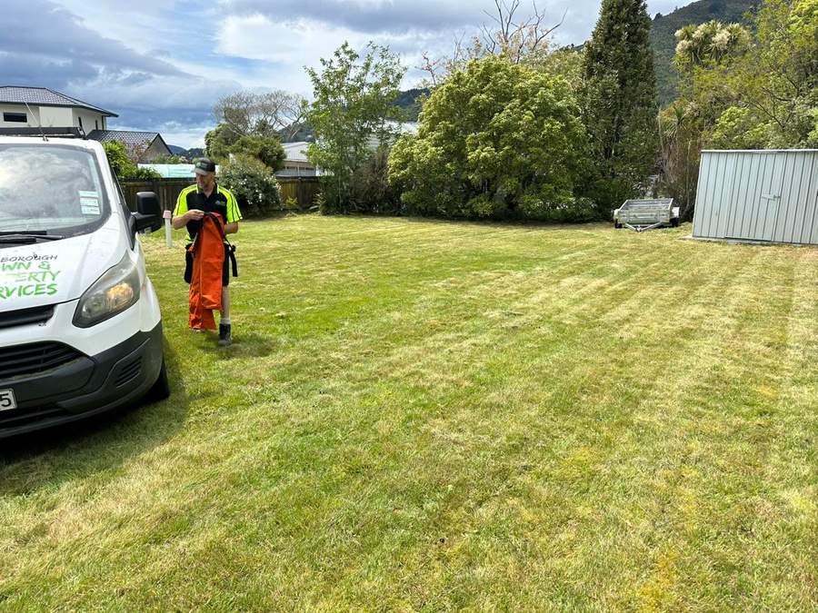 Team member beside the van after mowing a backyard