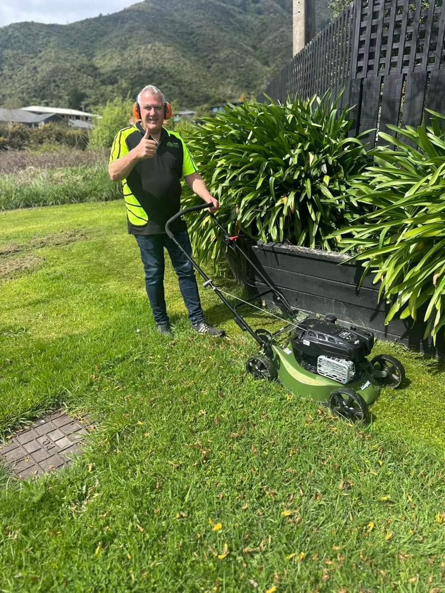 Marlborough Lawns team member with a push mower, thumbs up